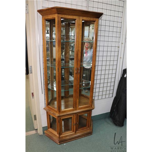 Trapezoid shaped illuminated display cabinet with mirrored back, three glass shelves on top section 