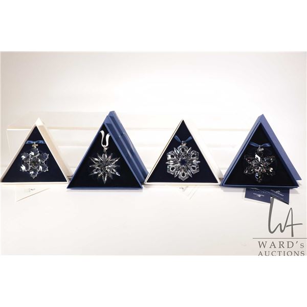 Four Swarovski crystal Christmas ornaments including 1996, 1999, 2008 and 2011
