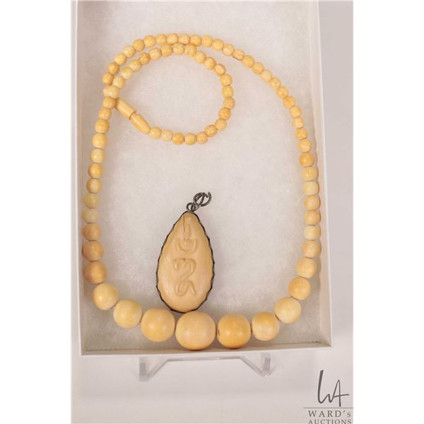 Graduated beaded ivory 17" necklace and a hand carved pendant. Can not be shipped outside of Canada.
