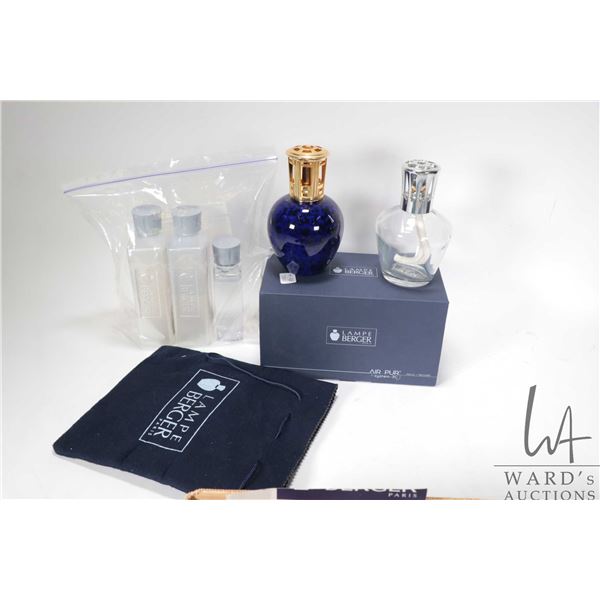 Two Lampe Berger fragrant oil burning lamps plus a two mostly full bottles and one half bottle of fr