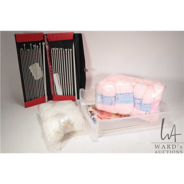 Twelve balls of pink and three balls of white double knitting baby wool plus a selection of knitting