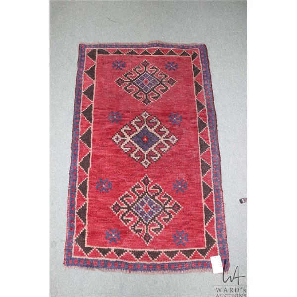 Small wool carpet with triple medallion, red background and highlights of blues, brown and taupe etc