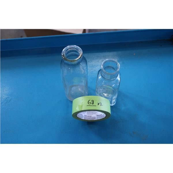 Two clear glass bottles: one cylindrical and one rectangular. The rectangular bottle is embossed wit
