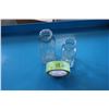 Image 1 : Two clear glass bottles: one cylindrical and one rectangular. The rectangular bottle is embossed wit