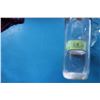 Image 2 : Two clear glass bottles: one cylindrical and one rectangular. The rectangular bottle is embossed wit