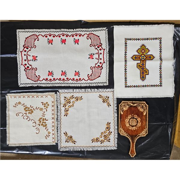 Four cross-stiched embroidery pieces and a wall hanging decorative bread board
