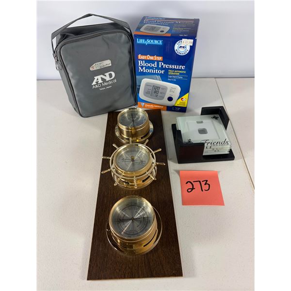 Mixed Household Items Including Blood Pressure Monitor and Decorative Weather Station