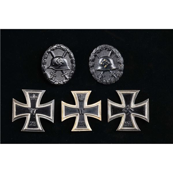 3 1ST IRON CROSSES AND 2 BLACK WOUND BADGES.
