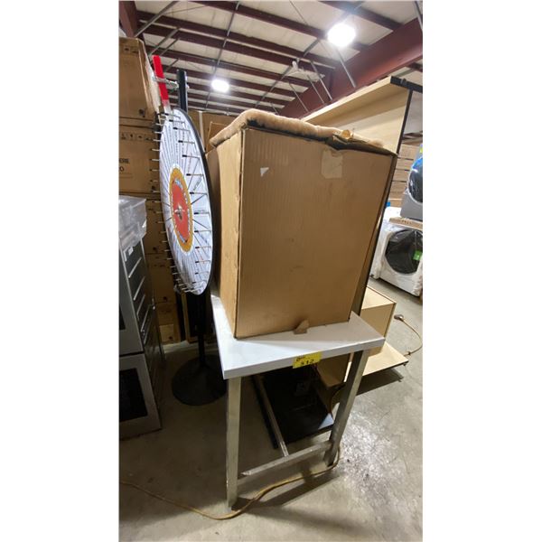 METAL FRAMED WHITE PLASTIC TOP TABLE WITH PRIZE WHEEL, BOX OF CUSHIONS & NAPOLEON DISPLAY RACK