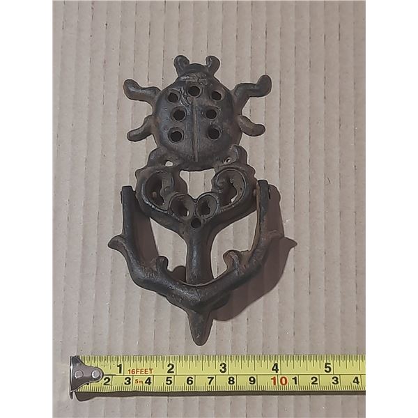 Vintage Cast iron door knocker featuring an ornate beetle or ladybug motif.