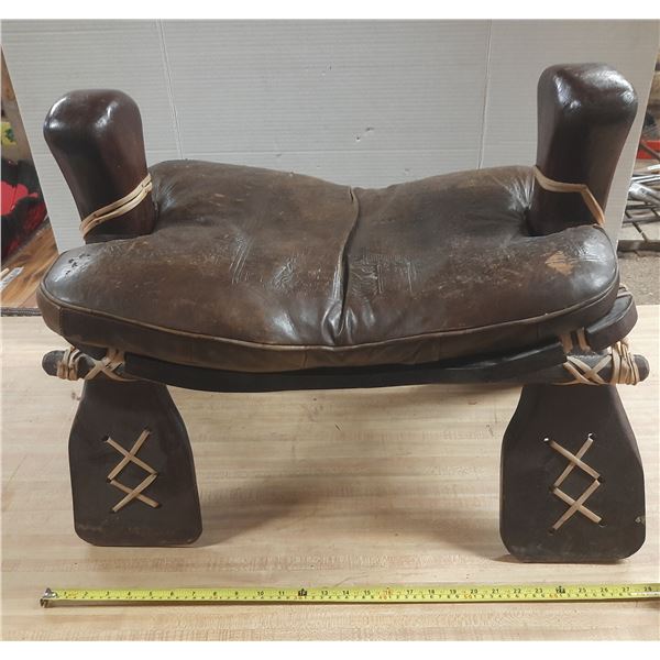 Vintage Middle Eastern or African camel saddle stool, featuring a dark brown leather seat and a carv