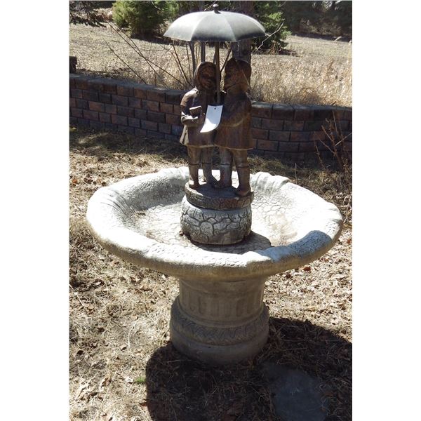 cement water fountain with two children under an umbrella