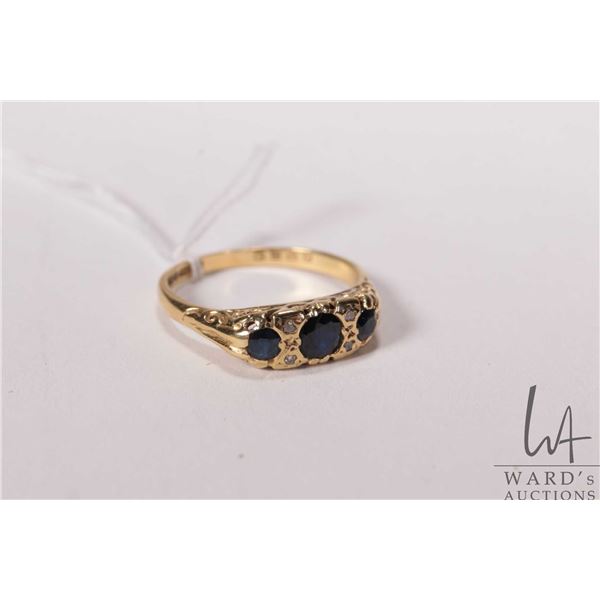 Vintage 18kt yellow gold ring set with three dark blue sapphire gemstones and four accent diamonds. 