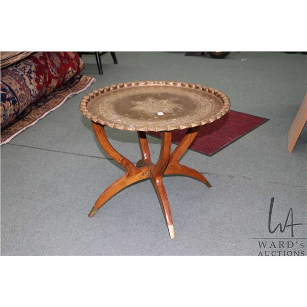 Hand chaised brass charger on folding wooden base, 18" H X 23" D