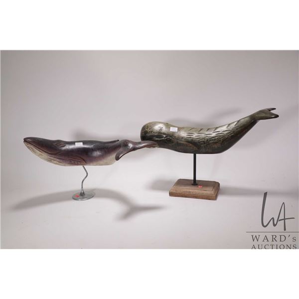 Two hand carved whale sculptures on stands including a sperm whale and a blue whale, each approximat
