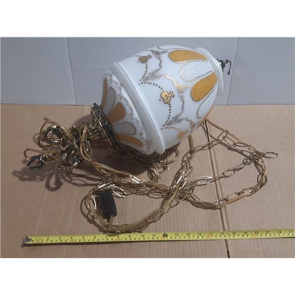 Vintage Hollywood Regency swag lamp features a milk glass globe adorned with gold embossed designs a