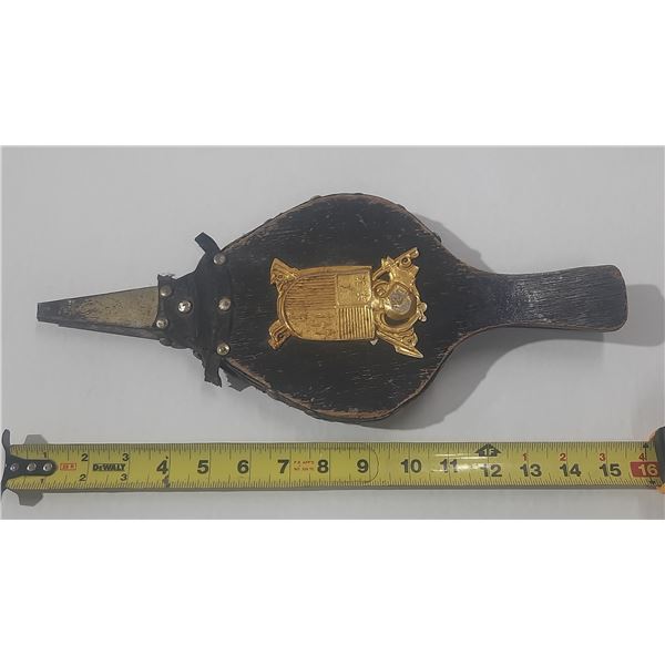 Vintage wood and leather fireplace bellows features a decorative coat of arms.