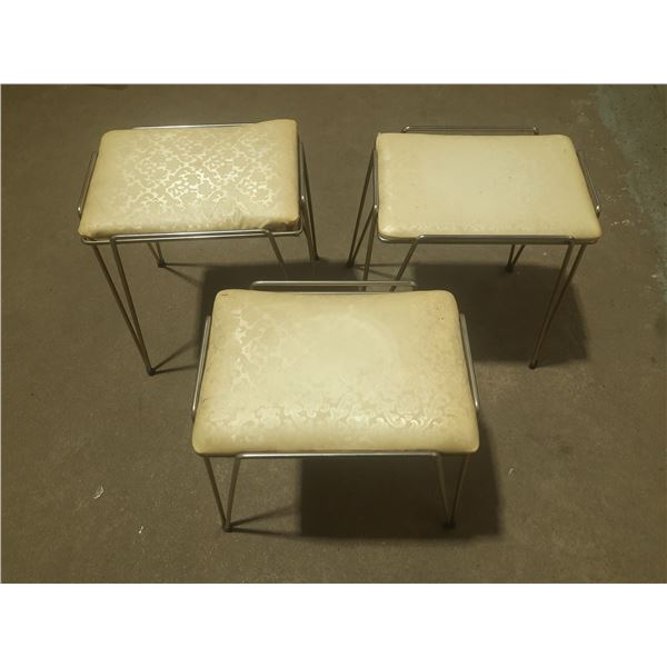 Vintage mid-century modern stacking stools feature cushioned vinyl seats with a white floral pattern