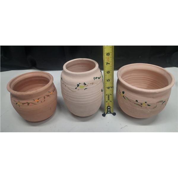 Vintage handmade terracotta or red clay earthenware pots used as planters or decorative vases.