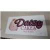 Image 1 : Daisy Cakes Metal Advertising Sign with Three-Tiered Cake Graphic 14”×22”