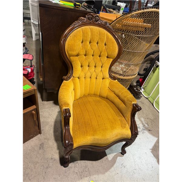 Victorian-style armchair features a high, button-tufted backrest in a mustard yellow velvet upholste