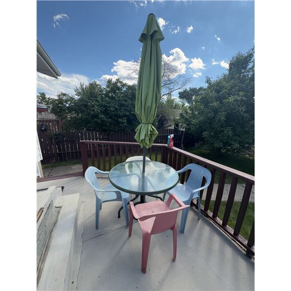 Patio Table With Glass Top, Four Plastic Chairs, and Green Umbrella