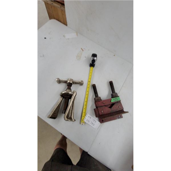 Gray Three-Jaw Gear Puller with T-Handle and Red Heavy-Duty Pipe Vise with Serrated Jaws