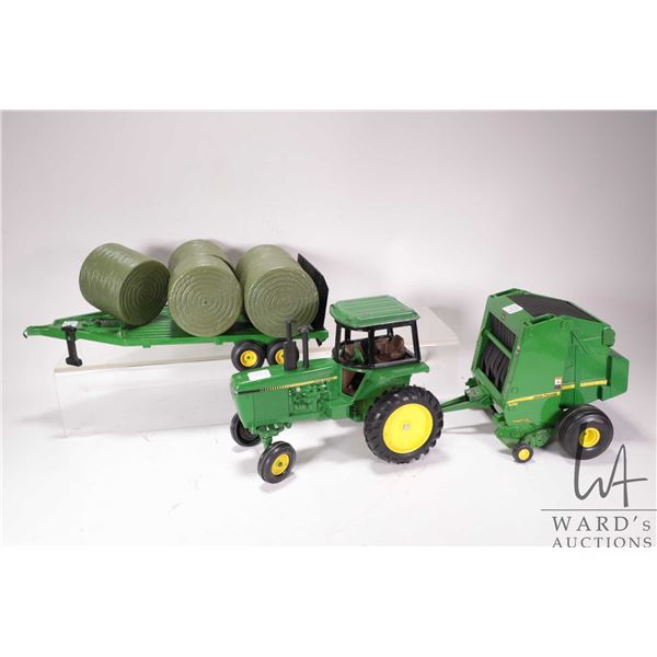 Three Ertl 1:18 scale die cast John Deere toys including 4450 tractor, 568 round bailer with hay bal