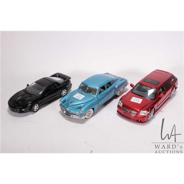 3 1/24 scale die cast model cars including a 1948 Tucker, a 2005 Dodge Magnum RT Custom, and 1999 Po