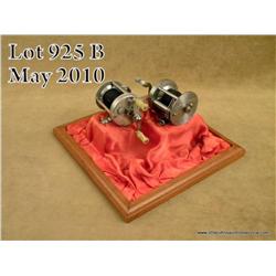 Collection of 2 Pslueger Trade Knotty Live Bait  Casting reels in four-sided glass and wood display 