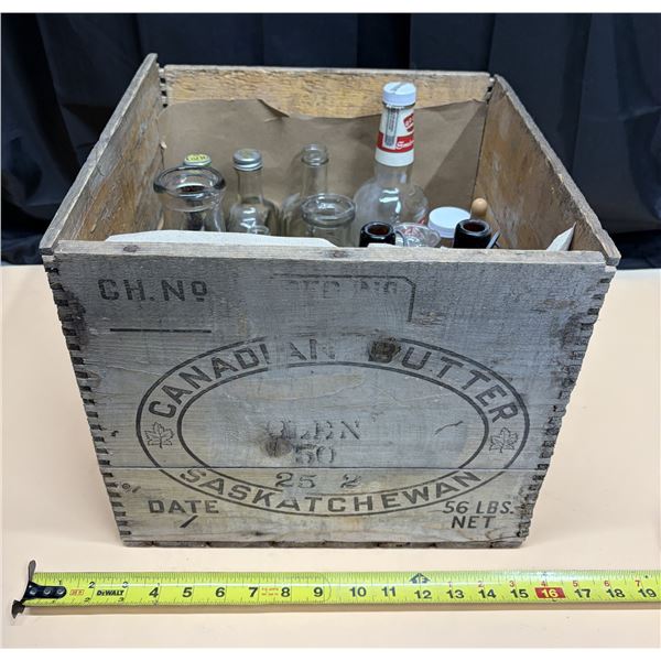 Vintage weathered wooden Canadian butter crate from Saskatchewan and assorted bottles.