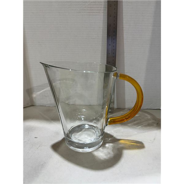 clear glass pitcher features a striking applied amber-yellow handle and a sleek tapered silhouette.