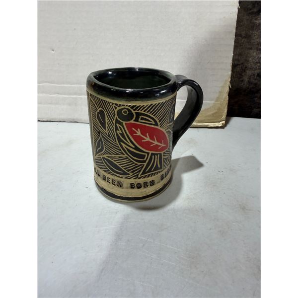 handcrafted ceramic mug featuring an etched sgraffito design of a red-bodied bird surrounded by foli