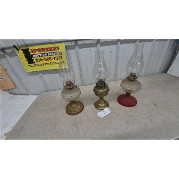 Three Oil Lamps: 1 Brass Base and Clear Glass Font, 1 Brass Base and Clear Glass Font, 1 Red Base.
