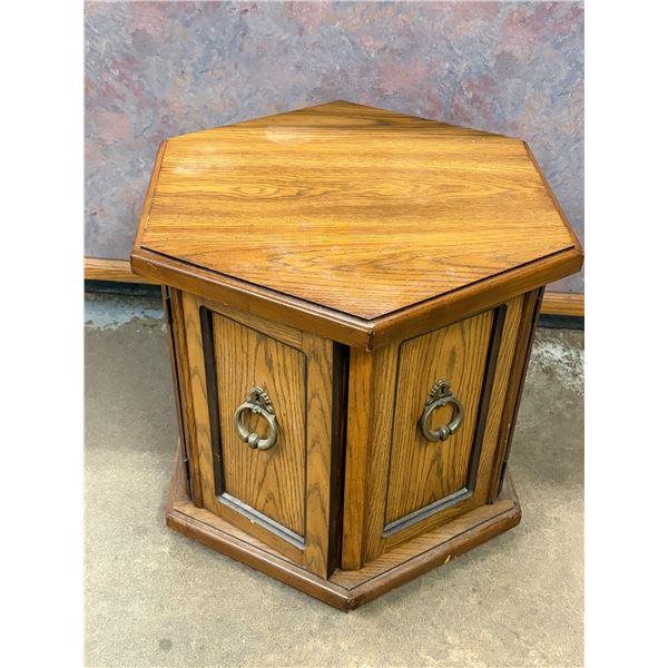 Vintage hexagonal oak wood end table featuring paneled cabinet doors with ornate brass ring pulls. (