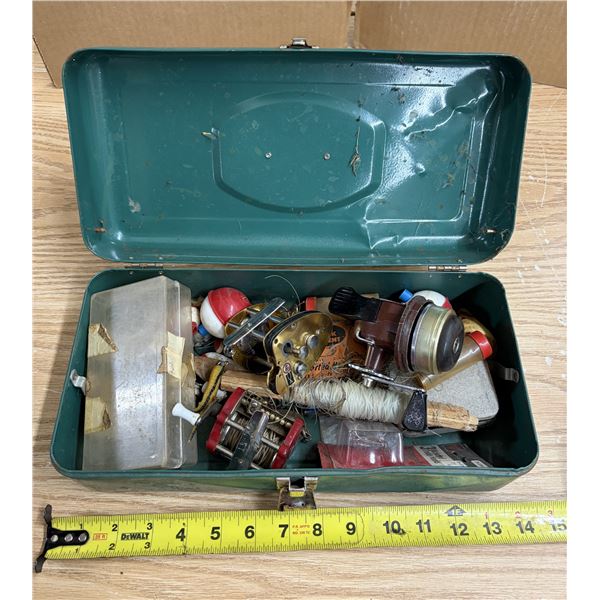 Vintage green metal fishing tackle box filled with older fishing gear and reels.