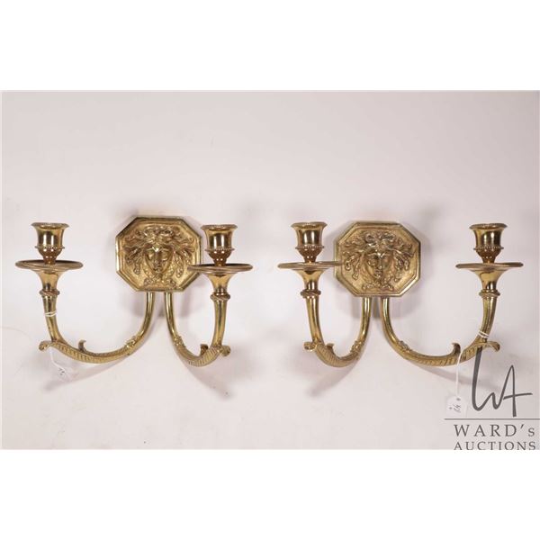 Pair of solid brass double candle sconces, each featuring a Sun King motif