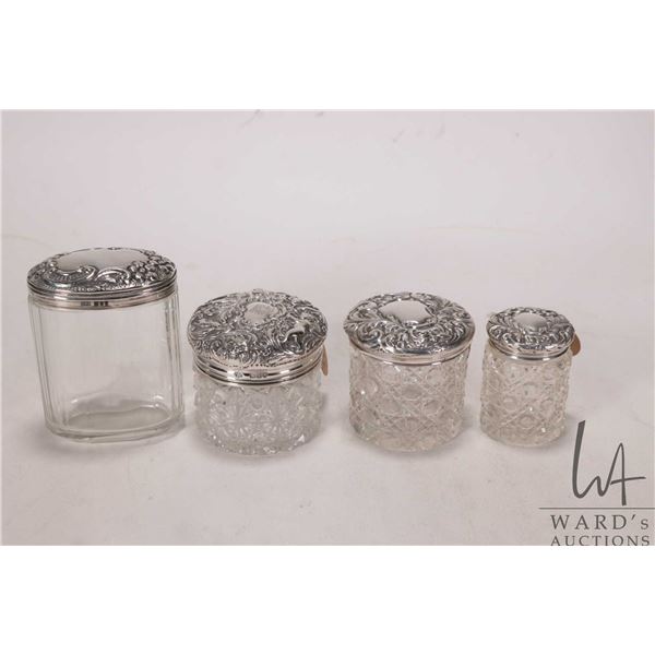 Four antique dresser jars, each with cut glass bases and sterling silver repoussee lids dated from 1