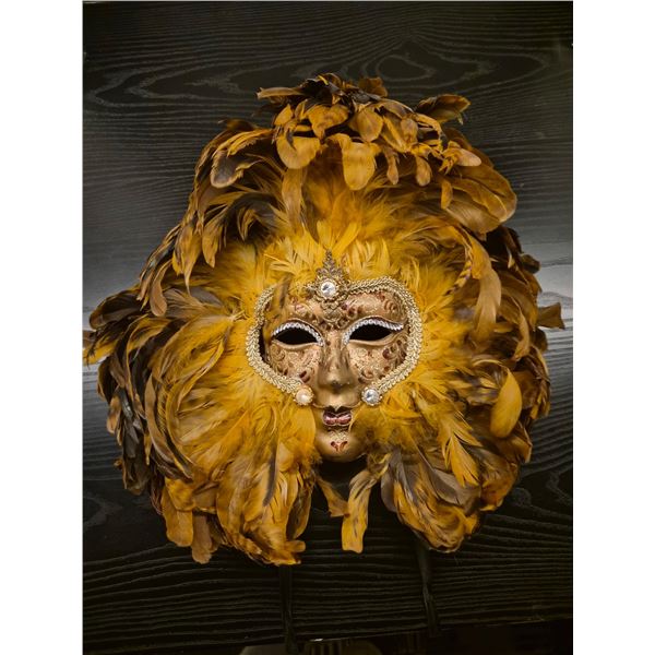 Wall mask featuring golden feathers