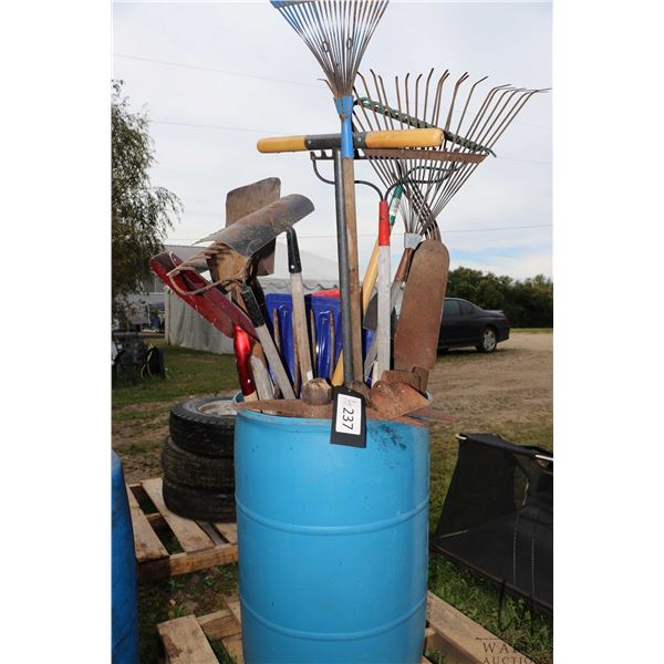 Rain barrel with large selection of rakes, shovels, picks etc.