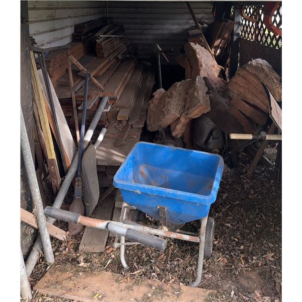 Building Materials and Tools Under Compound Including Wheelbarrow, Lumber, Pipes