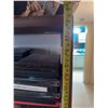 Image 18 : Wood and Glass Shelf Unit With DVDs, Remote Controls, Plush Tiger, and Decor Items
