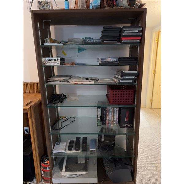 Wood and Glass Shelf Unit With DVDs, Remote Controls, Plush Tiger, and Decor Items