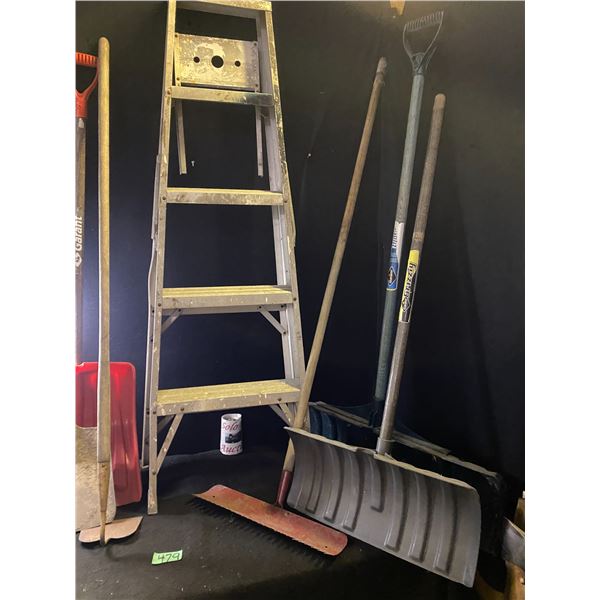 Assorted garden tools including shovels, rake, step ladder
