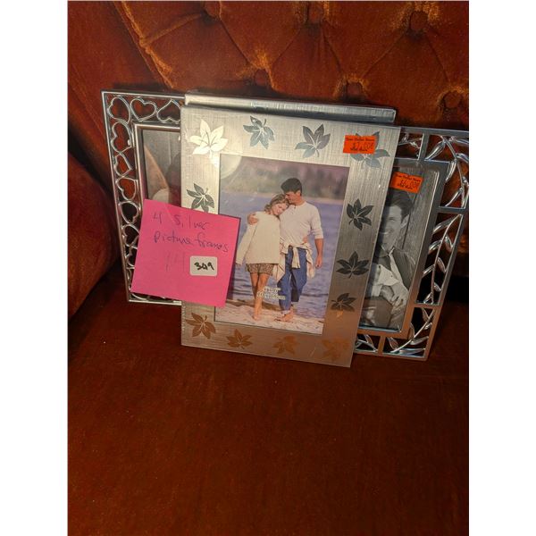 Four new, silver picture frames, 4x6 inches. Two with solid frame and leaves, two with hearts and vi