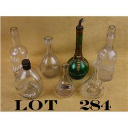Collectible lot of seven back bar bottles  including a scalloped bottle marked in white  enamel “Bla