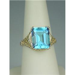 Pleasant 14 karat yellow gold ladies filigree  design ring set with a center emerald cut  Swiss blue