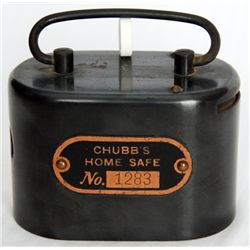CHUBB’S HOME SAFE. An oval steel satchel bank. Coin slot at right. Banknote hole at left. Handle at 