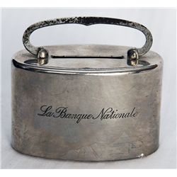 LA BANQUE NATIONALE, engraved on side of bank. An oval satchel bank. Coin slot on top. Handle at top