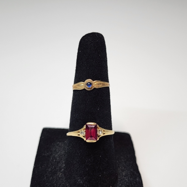 Two 10K Yellow Gold Rings: Blue Stone Size 3, Red Stone Size 7 - Total Weight: 1.7g